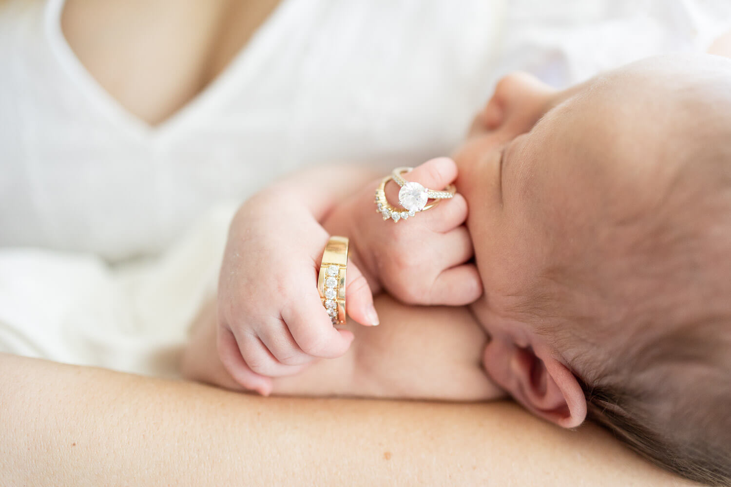 newborn with parents' rings on her fingers